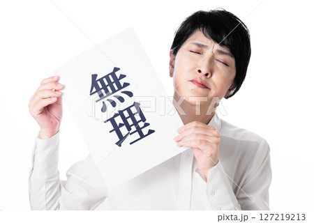 無理と書かれた紙を持ち顔をしかめる白いシャツを着た中年女性 無理と書かれた紙を持ち顔をしかめる白いシャツを着た中年女性 127219213