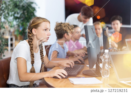 Portrait of teen schoolgirl sitting at table in computer class during lesson, smiling at camera. Concept of teenagers and technologies 127219231