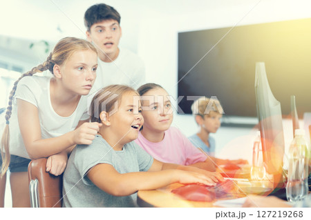 Preteen boys and girls working on computer together with teacher in IT cabinet 127219268