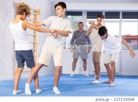 Diligent preteen student practicing self-defense techniques in pairs Diligent preteen student practicing self-defense techniques in pairs 127219306