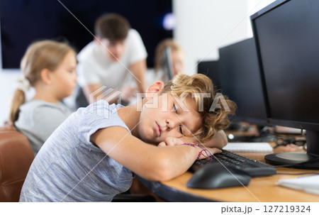 Tired male schoolgirl fell asleep on computer keyboard in class Tired male schoolgirl fell asleep on computer keyboard in class 127219324