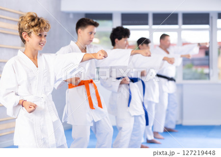 Preteen attendee of karate classes practicing kata standing in row with others 127219448