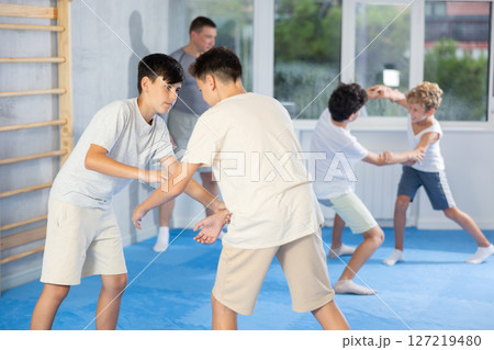 Teenage boys sparring in training room during self-defence workout Teenage boys sparring in training room during self-defence workout 127219480