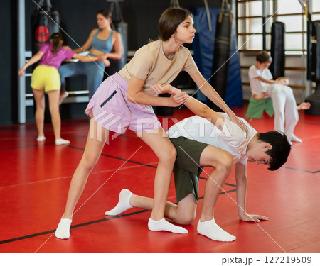 Teenage girl sparring with boy during training 127219509