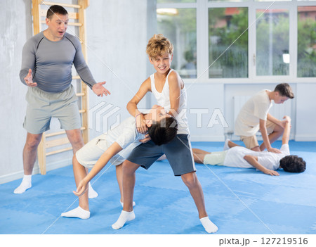 Teens applying inverted headlock in sparring during self-defense training 127219516