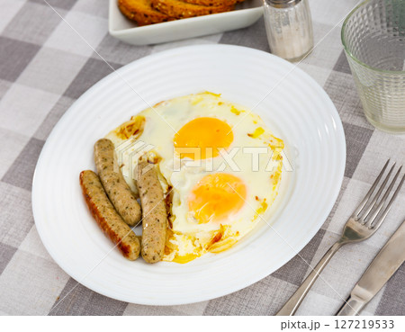 Fried eggs with onions served with sausage Fried eggs with onions served with sausage 127219533