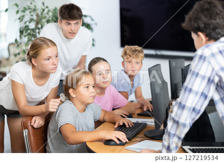 Computer lesson in classroom - classmates solve problems on computer together 127219534