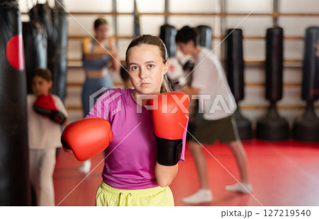 Teen girl in boxing gloves in training Teen girl in boxing gloves in training 127219540
