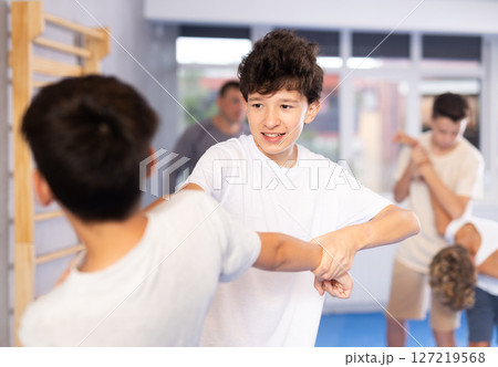 Diligent preteen student practicing self-defense techniques in pairs Diligent preteen student practicing self-defense techniques in pairs 127219568