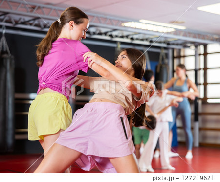 Purposeful engrossed teen girls train during self-defense fight training session in gym 127219621