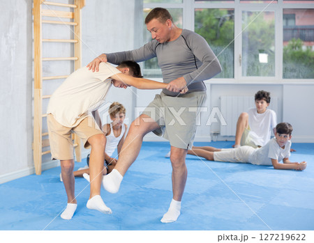 self-defense trainer performing foot sweep during simulated sparring with teenager self-defense trainer performing foot sweep during simulated sparring with teenager 127219622