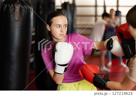 Teen girls fight with feet and hands, using all strength, courage. Kickboxing and boxing lesson 127219628