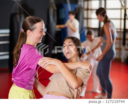 Purposeful engrossed teen girls train during self-defense fight training session in gym 127219744