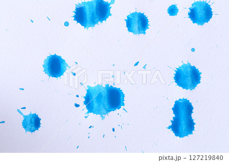 Blue color paint drops on paper, causing dispersion of color. 127219840
