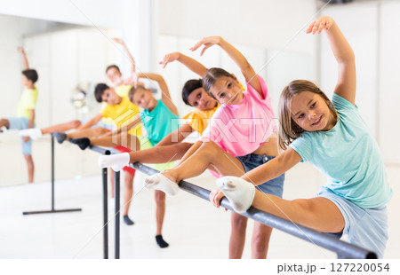 Group of children doing leg stretch at ballet barre Group of children doing leg stretch at ballet barre 127220054