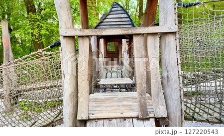 Discover a charming wooden playground with a rope bridge, ladder, and house 127220543