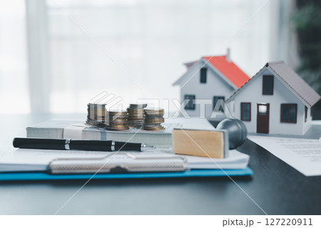 Rubber stamp calculator and loan house model on table with home loan approved on loan application form document paper, approval business finance economy commercial real estate investments concept. 127220911