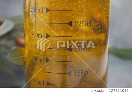 Carefully measuring oil using a transparent glass jug along with a scale 127221055