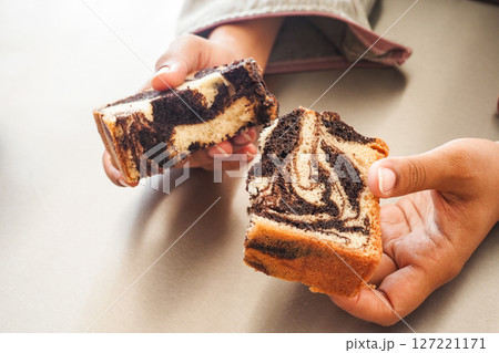 Delicious and scrumptious slices of swirled marble cake held in hands 127221171