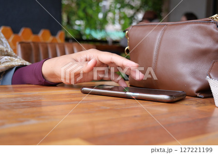 A hand grabbing and picking up mobile phone on the table. 127221199
