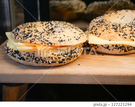 Enjoy a sesame seed bagel with cheese and fresh tomato slices 127221294