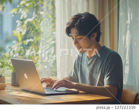 自宅でパソコン作業に集中する若い男性のリモートワーク風景 127221330