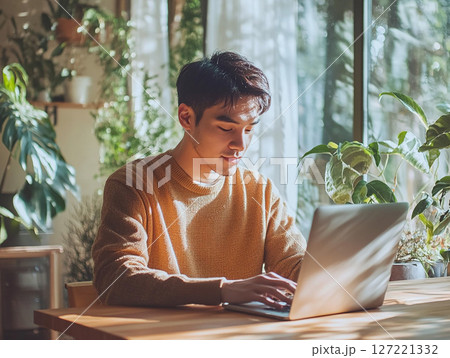自宅でパソコン作業に集中する若い男性のリモートワーク風景 自宅でパソコン作業に集中する若い男性のリモートワーク風景 127221332
