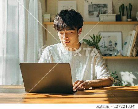 自宅でパソコン作業に集中する若い男性のリモートワーク風景 自宅でパソコン作業に集中する若い男性のリモートワーク風景 127221334