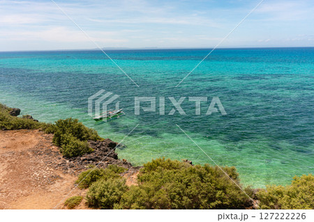 Boat over the sea. Beach with corals and clear sea water with sun reflection. Bantayan Island, Cebu, Philippines. Boat over the sea. Beach with corals and clear sea water with sun reflection. Bantayan Island, Cebu, Philippines. 127222226