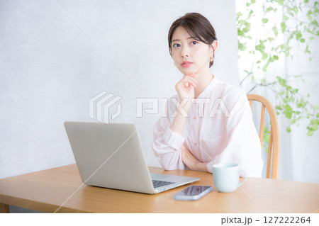 パソコンの前で考える　オフィスカジュアルのイメージ　シアーシャツの女性転職どうしようかな？カメラ目線 127222264