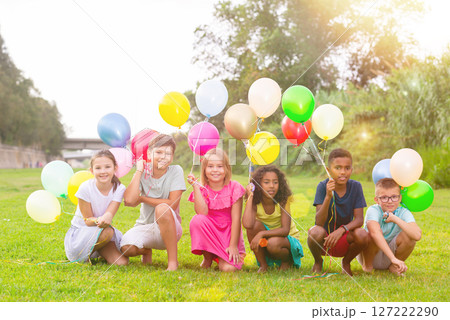 Barefoot kids playing with balloons on grass 127222290