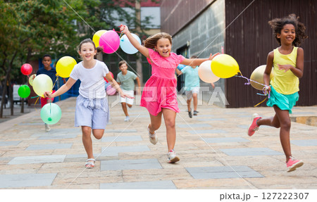 Cheerful preteen girls and boys with balloons running on city street Cheerful preteen girls and boys with balloons running on city street 127222307