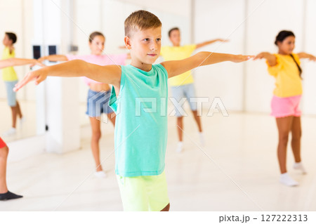 Preteen boy doing stretching workout before training in choreography class Preteen boy doing stretching workout before training in choreography class 127222313