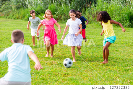 Happy preteen girls and boys playing football on green lawn Happy preteen girls and boys playing football on green lawn 127222383