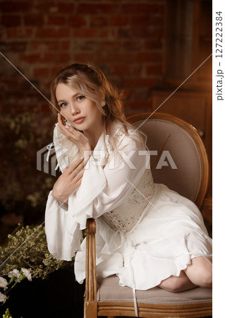 Woman in white dress sitting on chair in conceptual indoor swamp art setup Woman in white dress sitting on chair in conceptual indoor swamp art setup 127222384