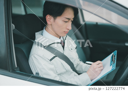 作業着にネクタイ姿の男性の車での外回り営業 127222774