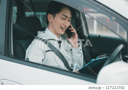 作業着にネクタイ姿の男性が車内で電話をする 作業着にネクタイ姿の男性が車内で電話をする 127222782