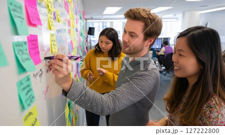Team brainstorming session in a modern office using sticky notes to generate ideas and solutions 127222800