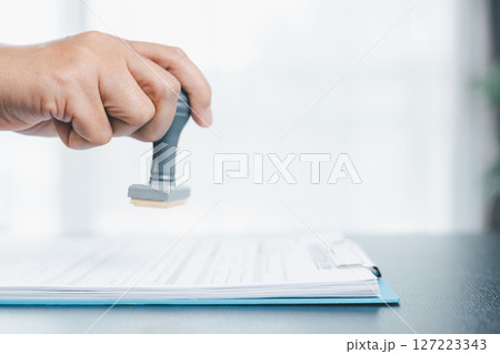 Businessman hands stamp approve on financial business approval document paper. Man hand accepted permit contract agreement. Broker manager sign contract bank guarantee approved stamp application form 127223343