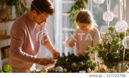 Family creates holiday decorations together in a cozy living room filled with greenery and warm light 127223786