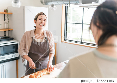 料理教室・クッキングスクールで料理を教える講師の女性と生徒の女性の後ろ姿 127224463