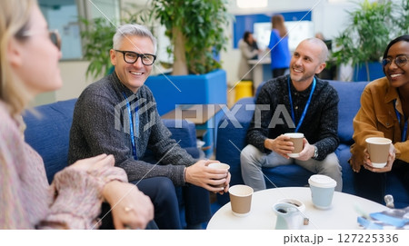 Colleagues enjoy coffee and conversation in a modern office space during a team meeting 127225336
