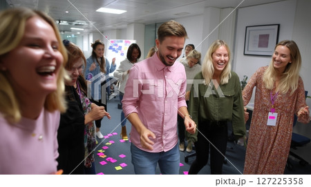 Team members engaged in laughter and fun during a collaborative activity in an office setting 127225358