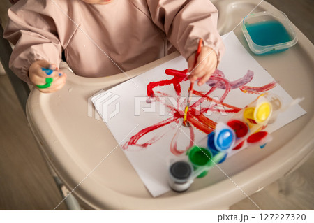 Little artist at work toddler girl painting with gouache paints at her play table. Cozy home environment and joyful learning. Little artist at work toddler girl painting with gouache paints at her play table. Cozy home environment and joyful learning. 127227320