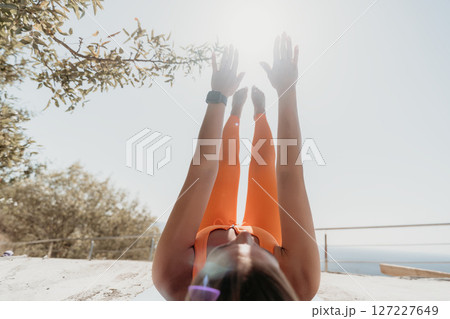 Woman in Orange Outfit Performing Yoga Pose in Sunny Outdoors 127227649