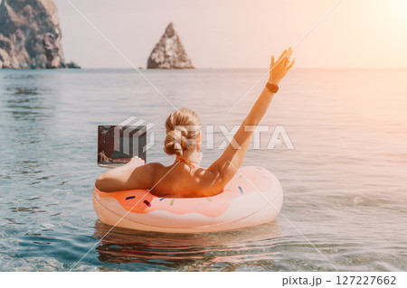 Woman, Laptop, Beach: Working remotely while floating on a donut pool float. 127227662