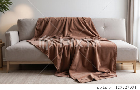 A mocha mousse-colored velvet throw blanket draped over a minimalist sofa. The plush, glossy texture of the velvet creates an 127227931