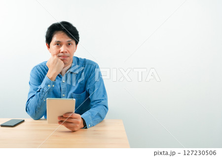 asian business man 30s to 40s with blue shirt use tablet for check profit of his startup business with good feeling and white isolated background asian business man 30s to 40s with blue shirt use tablet for check profit of his startup business with good feeling and white isolated background 127230506