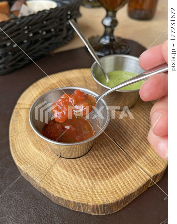 Tomato, green sauce for fried meat in metal sauce boats. Food on wooden stand. 127231672