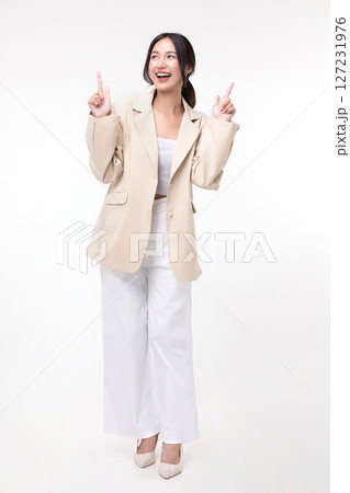 Happy Asian business woman in blazer pointing finger isolated on white background. 127231976